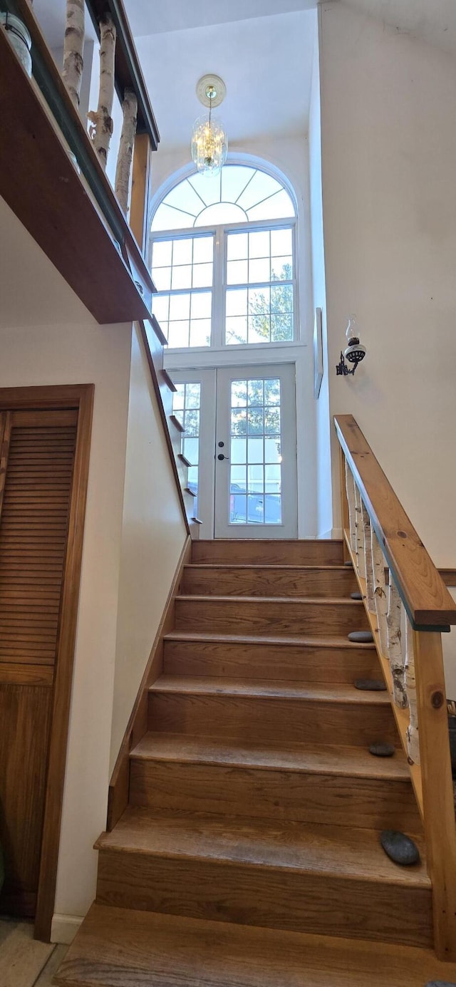 stairs featuring a notable chandelier and a towering ceiling