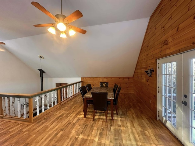 dining space with wooden walls, light hardwood / wood-style floors, and vaulted ceiling