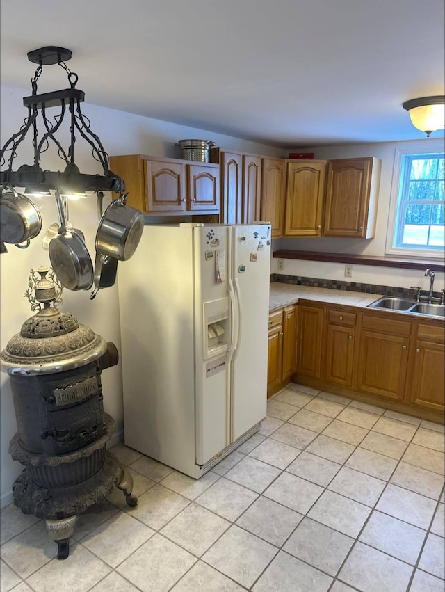 kitchen featuring pendant lighting, white fridge with ice dispenser, sink, and light tile patterned floors