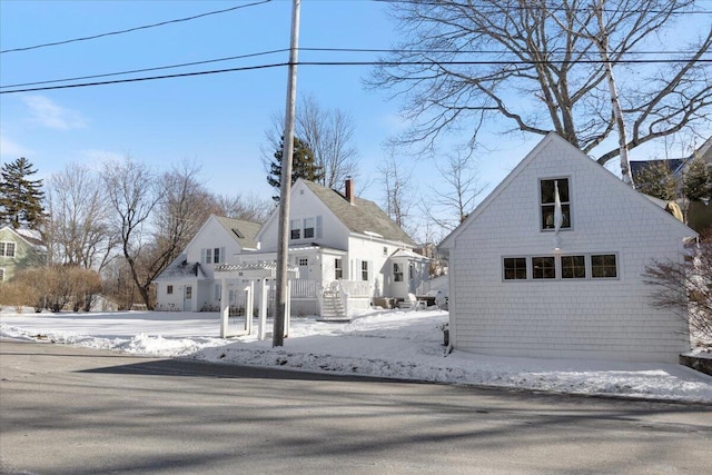 snow covered rear of property featuring an outbuilding and a garage