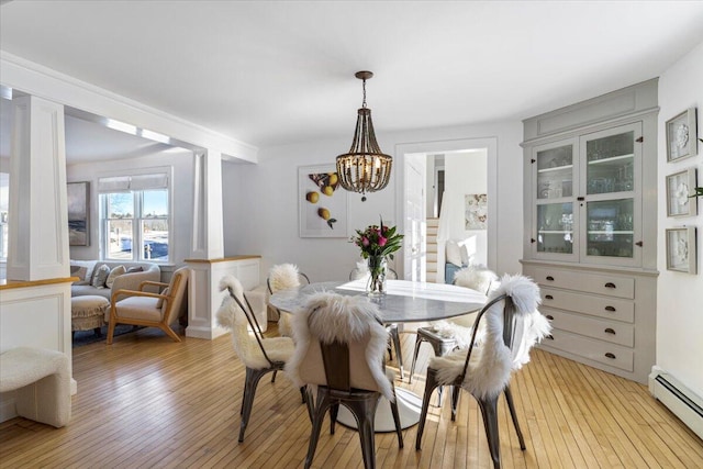 dining area featuring a baseboard heating unit, a notable chandelier, and light hardwood / wood-style flooring