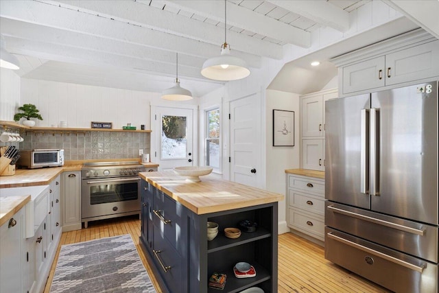 kitchen with wood counters, white cabinetry, decorative light fixtures, premium appliances, and beam ceiling