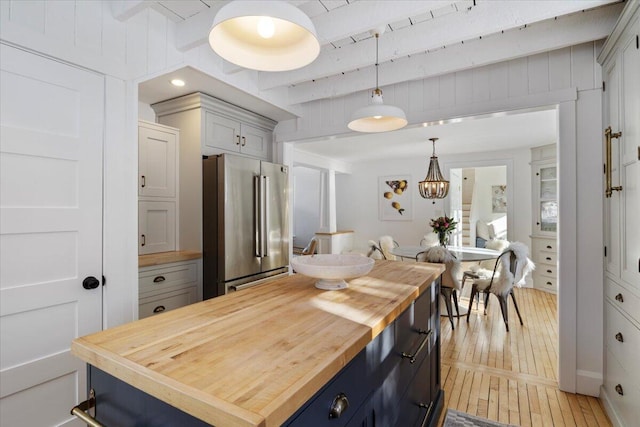 kitchen featuring wood counters, high end refrigerator, a center island, hanging light fixtures, and white cabinets