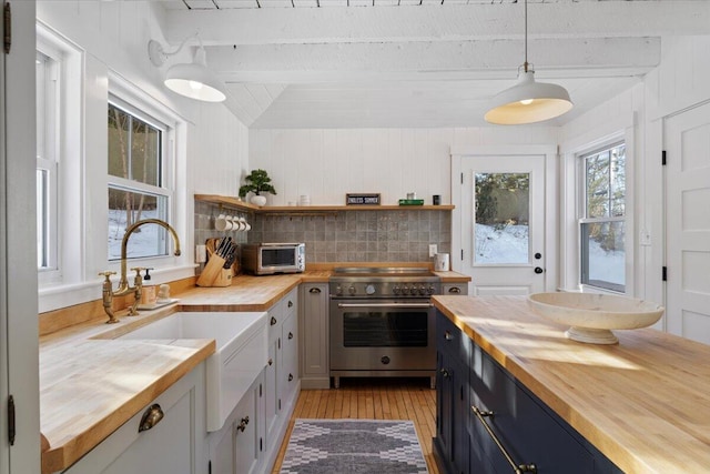 kitchen featuring white cabinetry, decorative light fixtures, butcher block counters, and high end stove