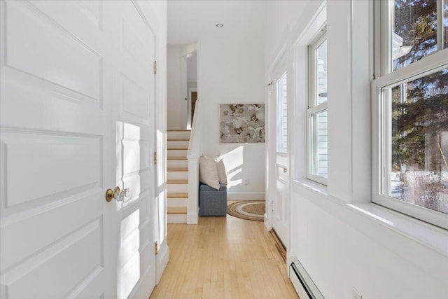 foyer entrance with baseboard heating, plenty of natural light, and light hardwood / wood-style flooring