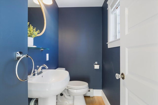 bathroom with baseboard heating, wood-type flooring, toilet, and sink