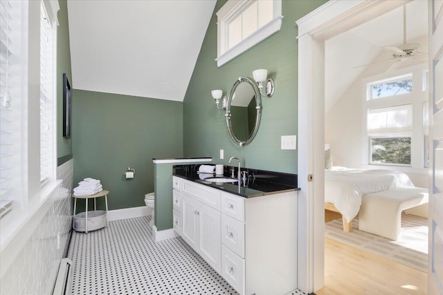 bathroom with vaulted ceiling, hardwood / wood-style flooring, vanity, ceiling fan, and toilet