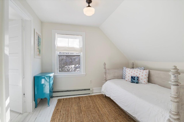 bedroom with lofted ceiling, a baseboard heating unit, and light wood-type flooring