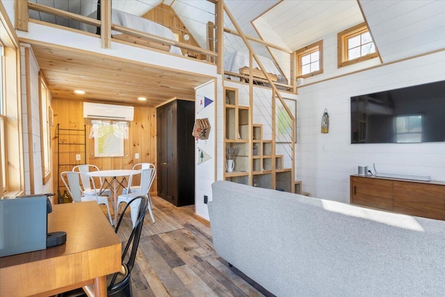 interior space featuring high vaulted ceiling, wooden walls, hardwood / wood-style floors, and an AC wall unit