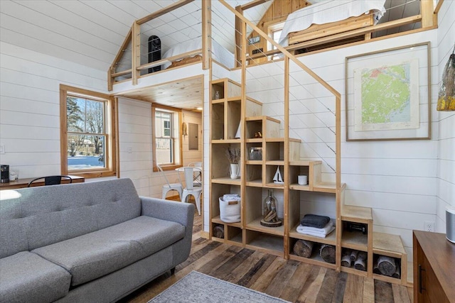 living room featuring wood-type flooring, wooden walls, and high vaulted ceiling