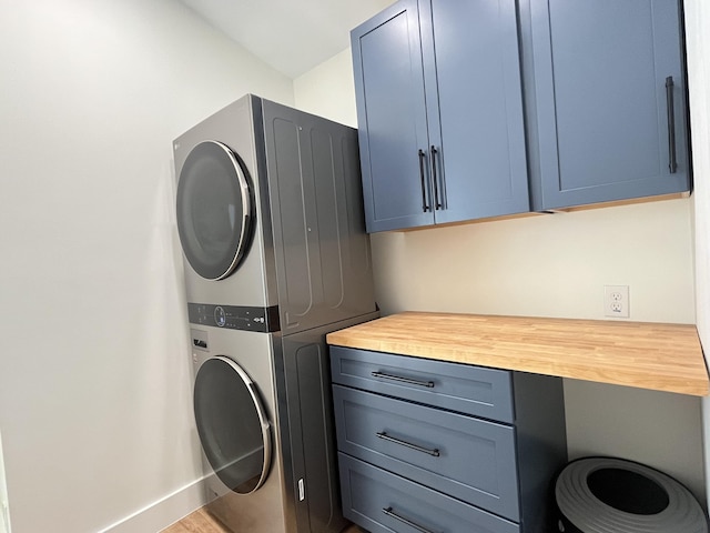 laundry room featuring cabinets and stacked washing maching and dryer