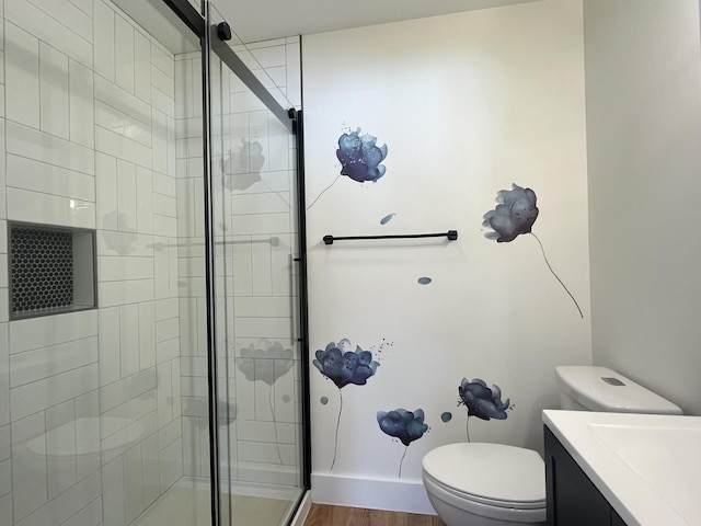 bathroom featuring vanity, hardwood / wood-style floors, a shower with shower door, and toilet