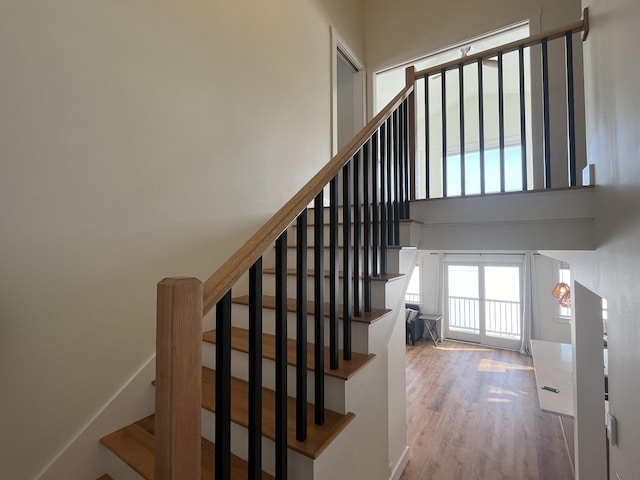 staircase featuring hardwood / wood-style floors and a high ceiling