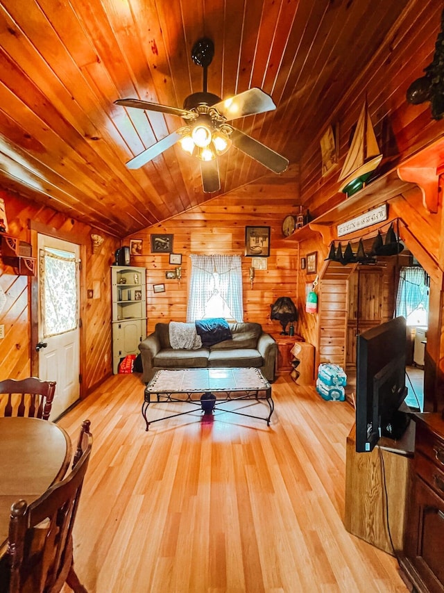 living room featuring wood ceiling, vaulted ceiling, light wood-type flooring, wooden walls, and ceiling fan