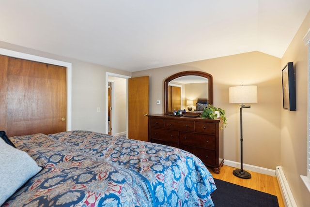 bedroom with light hardwood / wood-style flooring, a baseboard radiator, and vaulted ceiling