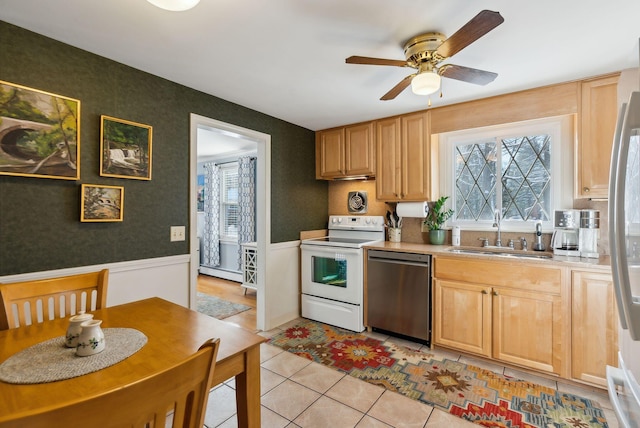 kitchen with sink, light tile patterned floors, light brown cabinets, a baseboard radiator, and stainless steel appliances