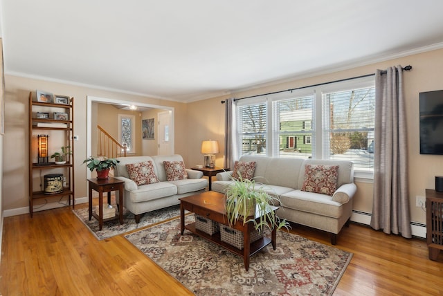 living room featuring crown molding, a baseboard radiator, ceiling fan, and light wood-type flooring