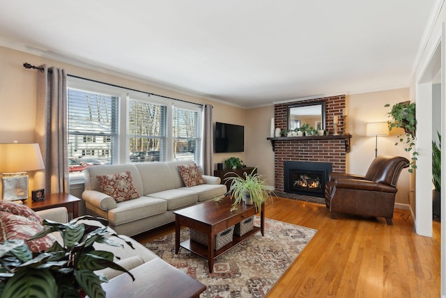 living room featuring a fireplace, ornamental molding, and light wood-type flooring