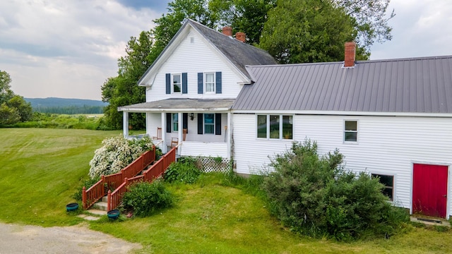 2382 Exeter Rd, Exeter, ME 04435 - view of front facade with covered porch, a chimney, a front yard, stairs, and a metal roof