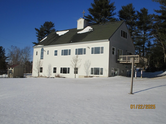 rear view of house featuring a storage unit and a deck