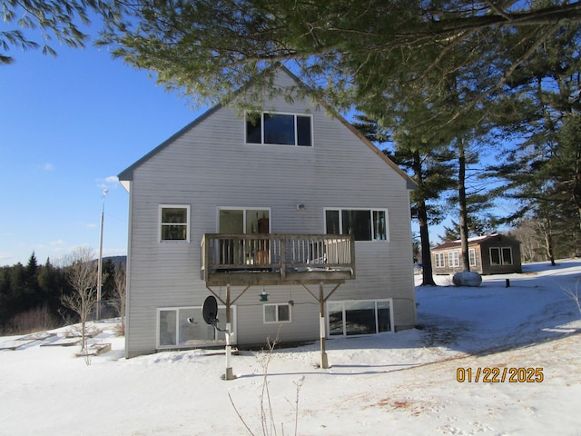 snow covered house featuring a wooden deck