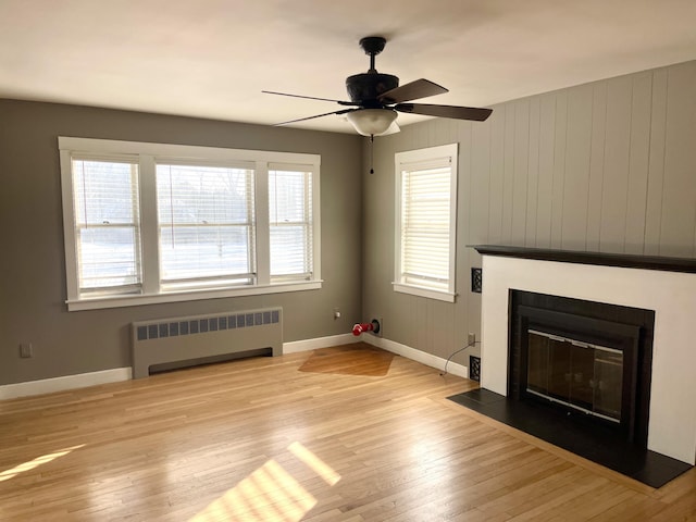 unfurnished living room with ceiling fan, radiator, and light wood-type flooring