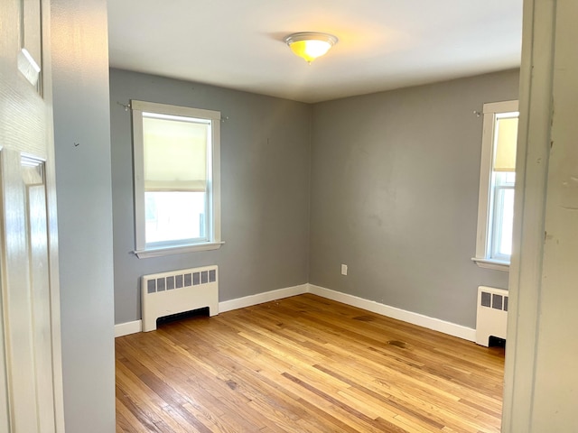 empty room featuring radiator heating unit and light hardwood / wood-style flooring