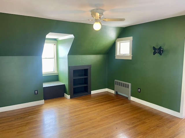 bonus room featuring radiator heating unit, light hardwood / wood-style floors, and a wealth of natural light