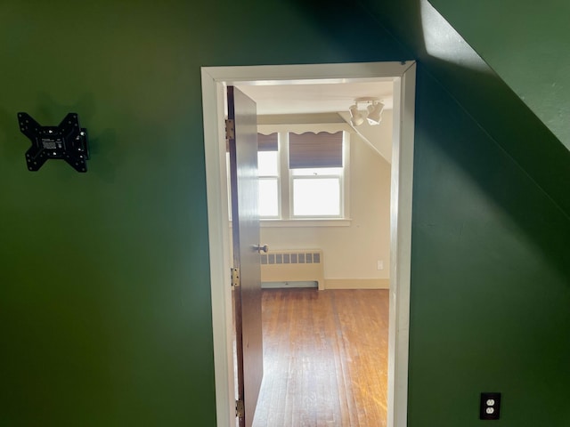 corridor with wood-type flooring and radiator heating unit