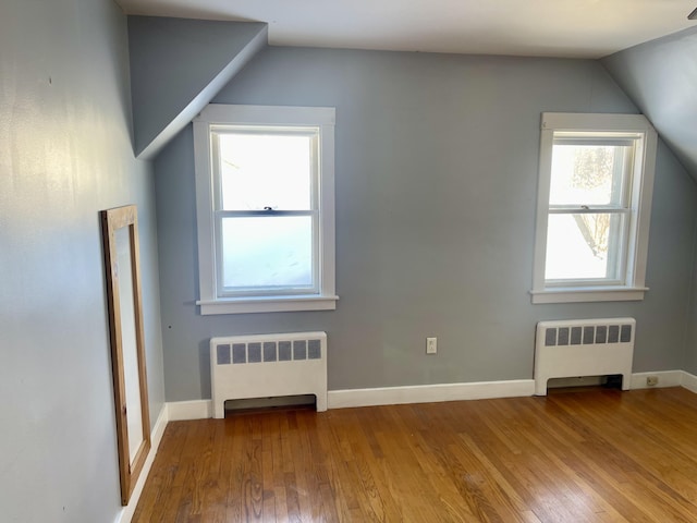 additional living space featuring wood-type flooring, vaulted ceiling, and radiator heating unit