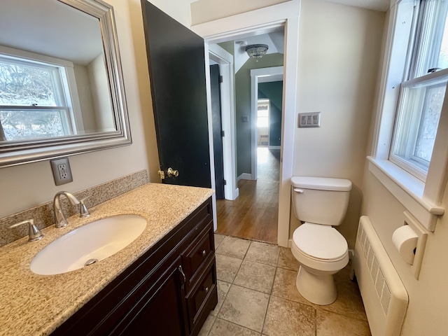 bathroom featuring vanity, radiator, tile patterned flooring, and toilet