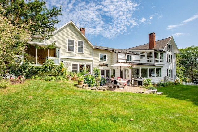 back of house with a sunroom, a patio area, and a lawn