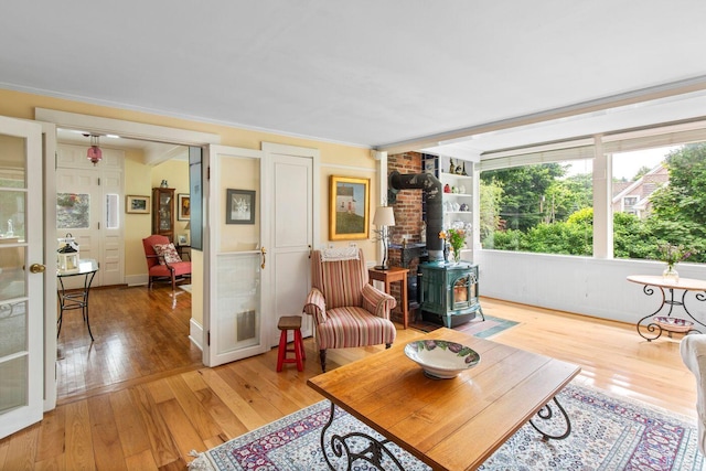 living room featuring crown molding, light hardwood / wood-style flooring, and a wood stove