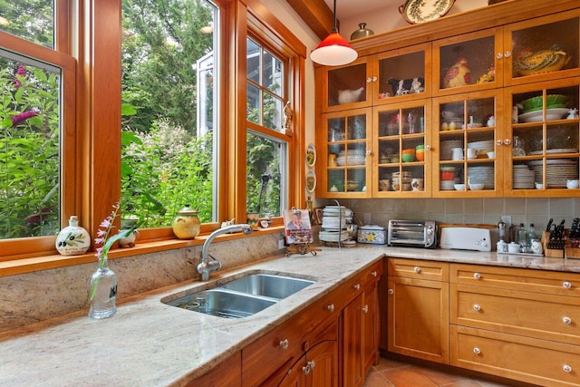 kitchen featuring sink, tasteful backsplash, hanging light fixtures, light tile patterned floors, and light stone countertops