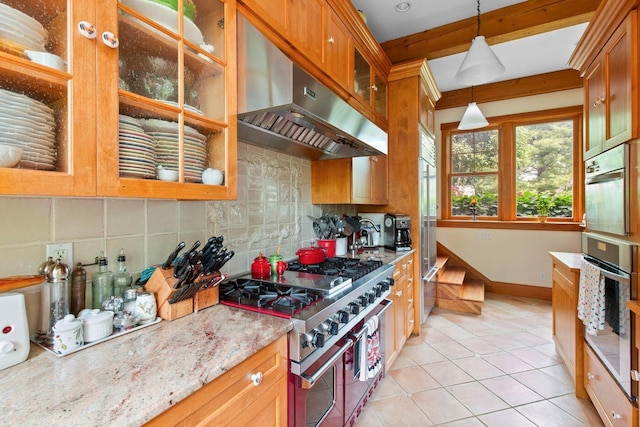 kitchen featuring decorative light fixtures, ventilation hood, double oven range, light stone countertops, and decorative backsplash