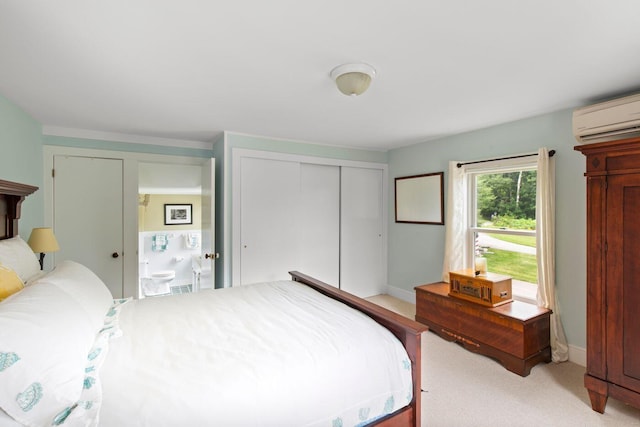 bedroom featuring an AC wall unit, light colored carpet, and ensuite bath