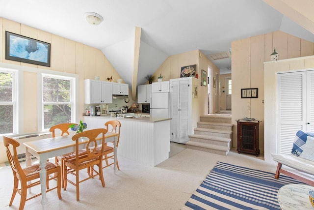 kitchen featuring white cabinetry, lofted ceiling, white refrigerator, light colored carpet, and kitchen peninsula