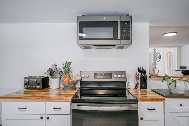 kitchen with white cabinetry, stainless steel appliances, and butcher block countertops