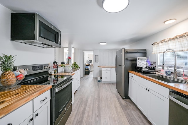 kitchen featuring appliances with stainless steel finishes, wood counters, white cabinetry, sink, and light hardwood / wood-style floors