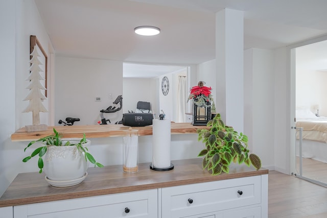 bar featuring butcher block counters, light hardwood / wood-style floors, and white cabinets