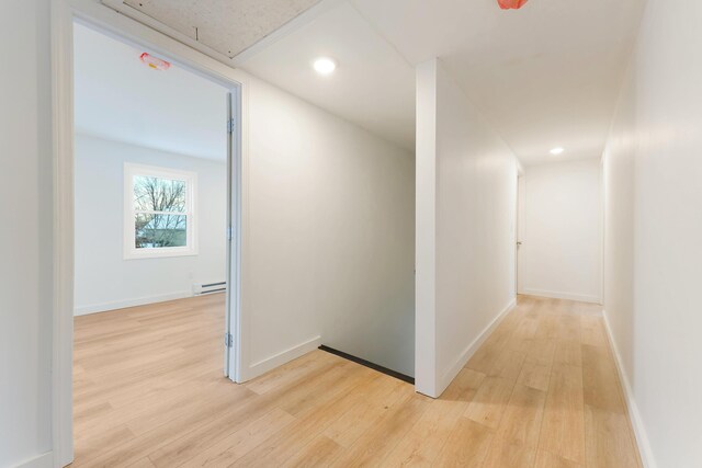 hallway featuring attic access, baseboard heating, baseboards, light wood finished floors, and recessed lighting