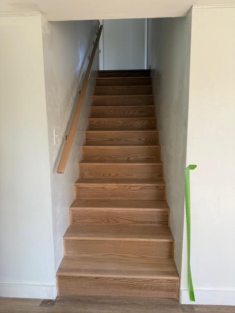 staircase featuring baseboards and wood finished floors
