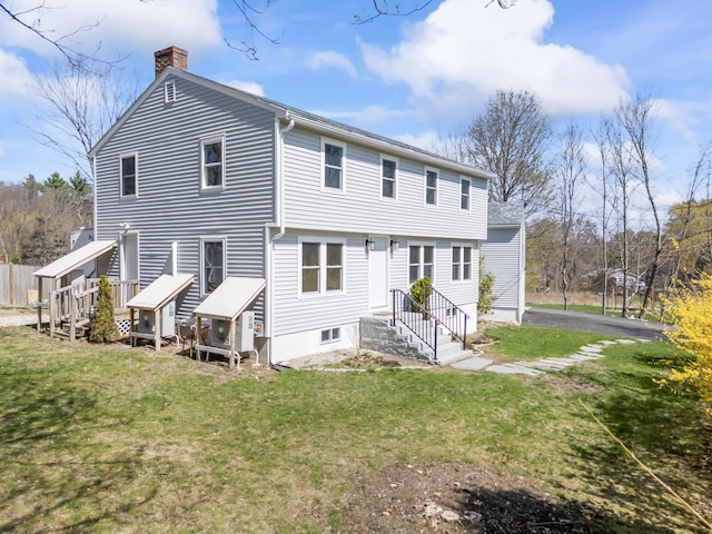 rear view of property featuring a lawn and a chimney