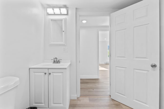 bathroom featuring baseboard heating, vanity, toilet, baseboards, and wood finished floors