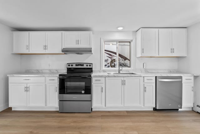 kitchen featuring white cabinetry, under cabinet range hood, light stone counters, a sink, and appliances with stainless steel finishes