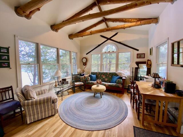 living room with light hardwood / wood-style flooring and vaulted ceiling with beams