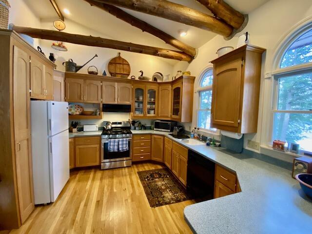 kitchen featuring light wood-type flooring, appliances with stainless steel finishes, sink, and vaulted ceiling with beams