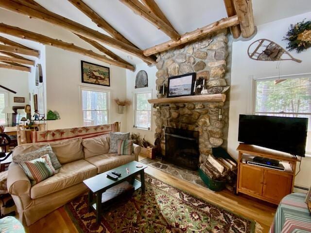 living room featuring lofted ceiling with beams, a baseboard radiator, a stone fireplace, and light hardwood / wood-style flooring