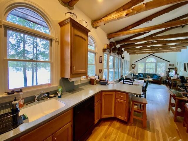 kitchen with lofted ceiling with beams, black dishwasher, sink, kitchen peninsula, and light hardwood / wood-style flooring