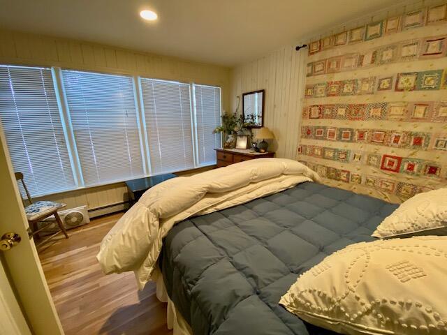 bedroom with a baseboard heating unit and wood-type flooring